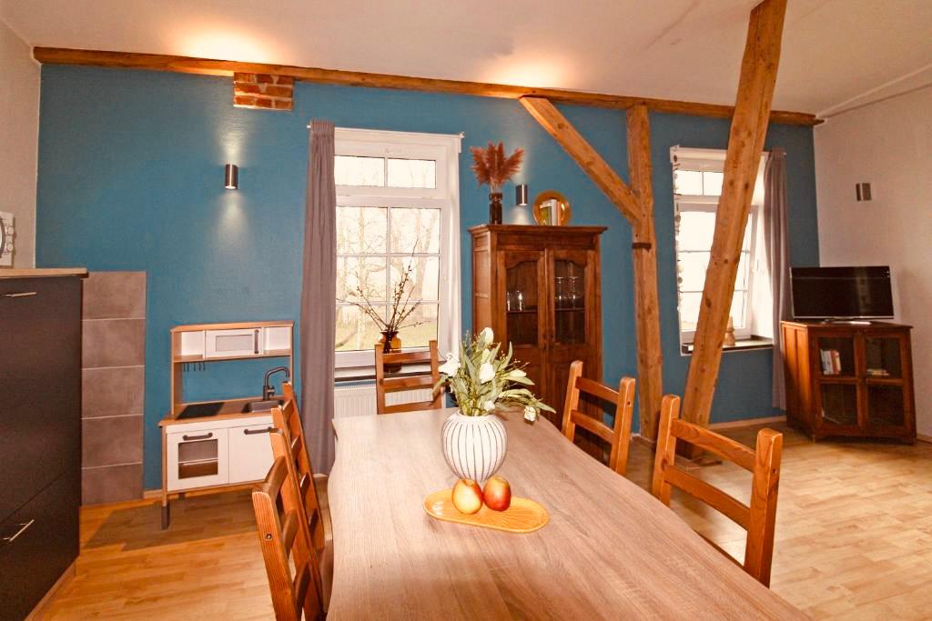 Geräumiger Wohn- und Essbereich in einer Ferienwohnung mit einer großen, rustikalen Essgruppe aus hellem Holz als zentralem Element.