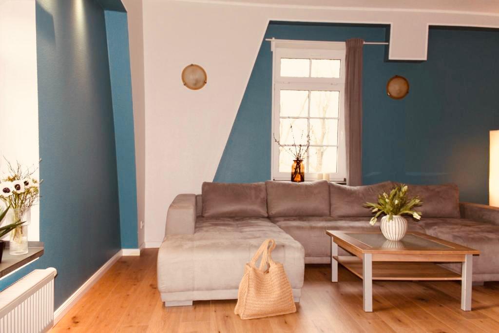 Modernes Wohnzimmer in einer Ferienwohnung mit einer großen, beigefarbenen Eckcouch und einem Couchtisch.