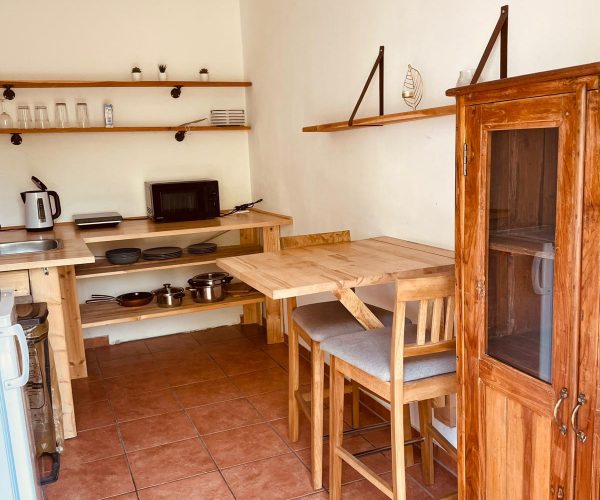 Kleine, funktional eingerichtete Ferienwohnung-Küche im Landhausstil mit hellbraunen Fliesen.