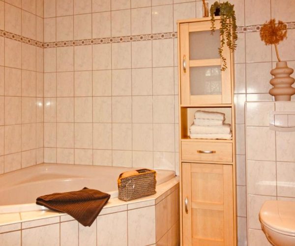 Geräumiges Badezimmer in einer Ferienwohnung mit einer großen Eckbadewanne und einem WC.
