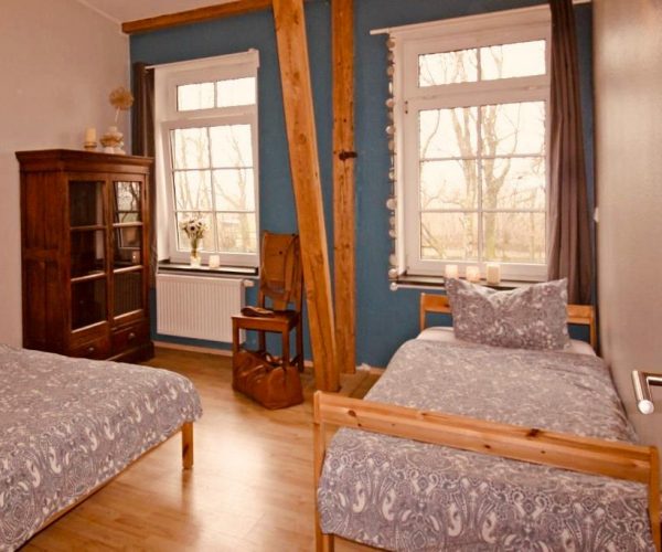 Schlafzimmer in einer Ferienwohnung mit zwei rustikalen Einzelbetten und gemusterter Bettwäsche.
