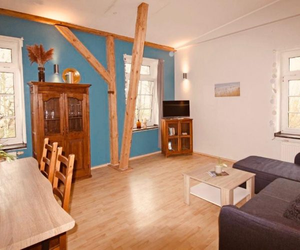 Geräumiger Wohn- und Essbereich in einer Ferienwohnung mit sichtbaren rustikalen Holzbalken.
