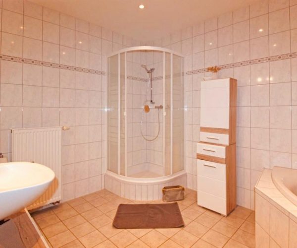 Modernes Badezimmer in einer Ferienwohnung, ausgestattet mit hellen Wand- und Bodenfliesen.