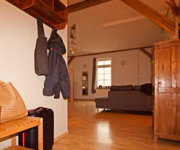 Eingangsbereich einer Ferienwohnung, der in einen geräumigen, offenen Wohnbereich führt.