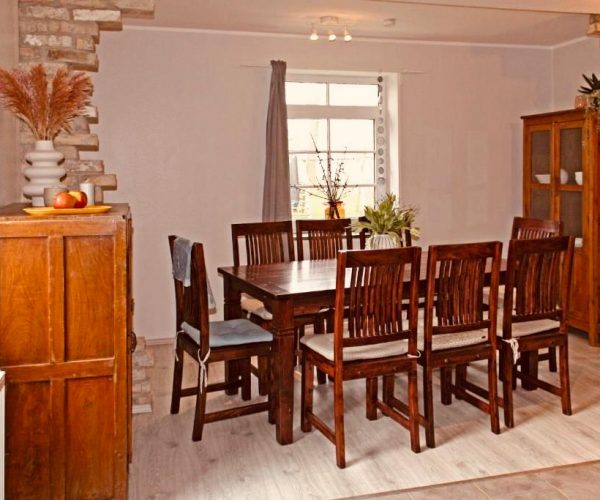 Rustikaler Essbereich in einer Ferienwohnung mit einem dunklen Holztisch und passenden Holzstühlen.