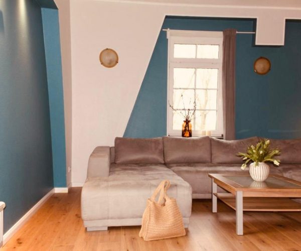 Modernes Wohnzimmer in einer Ferienwohnung mit einer großen, beigefarbenen Eckcouch und einem Couchtisch.