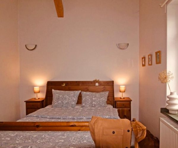 Gemütliches Schlafzimmer in einer Ferienwohnung mit einem Doppelbett und einem rustikalen Holzbettrahmen.